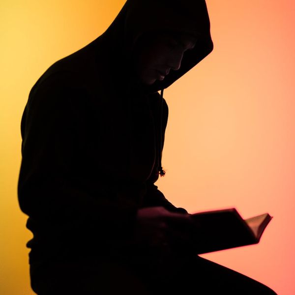 Silhouette of a person in an empowered yoga pose against a vibrant background.