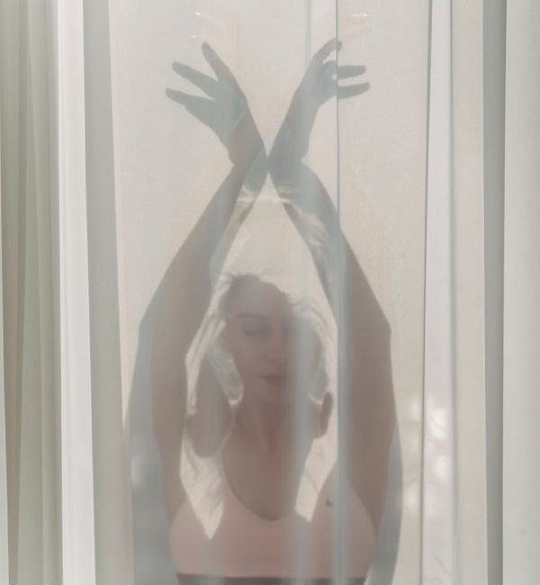 Woman in a peaceful yoga pose, bathed in soft emerald light.